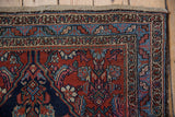 Vintage Bibikabad rug corner showing cherry red field, navy blue borders with intricate patterns, and mostly secure edge wear.