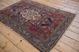 Corner of vintage Bibikabad rug, cherry red field, blue and ivory floral border, secure end.