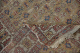 Antique Caucasian rug showing worn saffron field, floral pomegranate pattern, and tattered fringe.