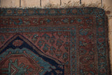 Vintage Kurdish Hamadan rug's tattered corner, featuring madder root red and sky blue floral patterns.