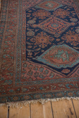 Vintage Kurdish Hamadan rug displaying navy field with blush floral motifs and tattered fringe.