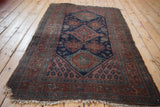 Worn corner of vintage Kurdish Hamadan rug, tattered fringe, navy and madder red motifs.