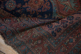 Folded vintage Kurdish Hamadan rug, showing hand-knotted pile, navy, madder red floral motifs, and visible wear.