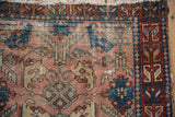 Antique Lilihan rug with dusty rose field, blue palmettes, red serpent border, and wear.