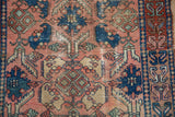 Antique Persian Lilihan rug detail: rust-red border with blue S-motifs and worn field.
