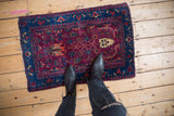 Tattered corner of a Farahan Sarouk rug, with deep burgundy, sapphire blue tulip motifs.