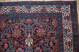 A vintage Malayer rug corner showing samovar stylized vinery against a navy blue ground.