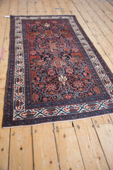 Angled view of a vintage Malayer runner with a navy blue field, geometric vinery, and ivory border.