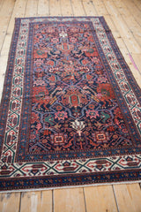 Vintage Malayer rug runner's complex geometric patterns and navy field seen from an angle.