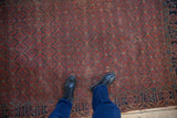 Antique Persian Qashqai rug detail: madder red lattice, navy love bird border, visible wear.