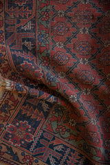Hand knotted antique Qashqai rug showing madder red panel lattice, navy geometric border, and aged pile texture.