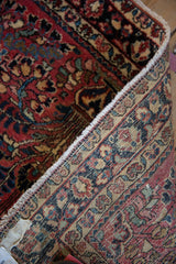 Close-up of the vintage Sarouk rug's woven backing and fringe, revealing brick red floral pile.