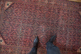 Vintage Farahan Sarouk rug corner, intricate Herati motifs in faded navy and terra cotta.