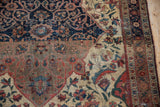 Antique Farahan Sarouk rug detail: navy blue medallion with arabesques merging into ivory field of floral vinery.