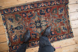 Worn vintage Lilihan rug with expressive floral palmettes, cherry red, navy, and green tones.