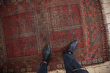 Vintage Ersari rug, black cherry red panels, navy geometric pattern, showing hard wear and holes.