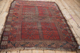 Detail of vintage Ersari rug with worn black cherry red field, navy, teal rams horn border.