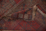 Folded vintage Ersari rug detail, showing tattered fringe and geometric border in red and navy.