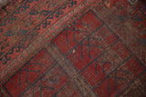 Hard wear, a visible hole, and geometric plant motifs on the Ersari rug in red and navy.