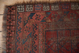 Tattered chocolate brown fringe and geometric red, teal, ivory border of a vintage Ersari rug.