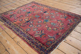 Vintage Lilihan rug corner showing time-softened raspberry field and triple meandering vine border.