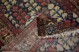 Close-up of antique Hamadan rug border with madder red turtle motif, worn navy field, and tattered fringe.