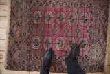 Antique Turkmen rug with abrashed magenta field, repeating guls, intricate borders, and visible age-related wear.