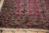Turkmen rug's multi-layered border, navy motifs, and frayed ivory fringe.