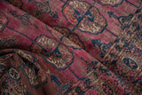 Folded antique Turkmen rug shows abrashed magenta pile and navy gul motifs.