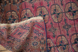 Antique Turkmen rug reverse, showing hand-knotted foundation and tattered ivory fringe.