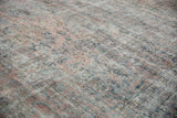 Distressed vintage Mahal rug texture showing worn floral motifs in dusty pink and teal.