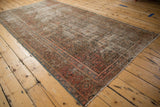 Distressed vintage Hamadan carpet showing faded dusty blush herati design and exposed foundation.