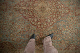 Distressed Kashan carpet with dusty blue, wine red floral motifs and visible foundation speckling.