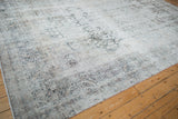 Worn texture and faded floral patterns on a distressed antique Kerman in ivory and charcoal.