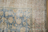 Worn corner of a vintage Meshed rug revealing the foundation and denim blue floral pattern.