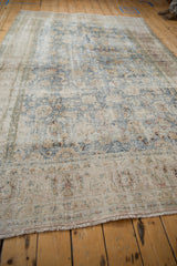 A long, angled view highlights the heavy, decorative wear on a vintage Persian Meshed carpet.