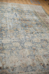 Close-up of the distressed Persian carpet's low pile and visible knot heads.