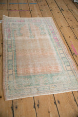 Angled view of a distressed Oushak prayer rug, highlighting its characterful wear and soft palette.