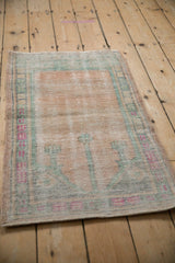 Angled view of a distressed Oushak mat, highlighting its low pile and significant, time-softened wear.