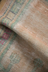 A gentle fold showing the soft, worn texture of the hand-knotted Oushak rug in pale apricot.