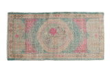 Distressed vintage Oushak runner with a faded floral medallion in ocean green and bubblegum pink.