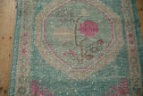 Worn texture of a pink rose motif within a distressed ocean green medallion.