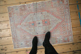 A person stands on a small vintage distressed Oushak rug, showing its scale and worn texture.