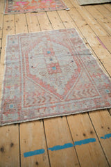 A distressed vintage Oushak rug from an angle, highlighting its pale orange medallion and worn texture.