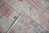 Corner of a distressed Oushak rug folded over, revealing the hand-knotted back and secured side cord.