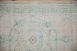 Textured close-up of distressed Oushak runner with faded green and cream patterns.