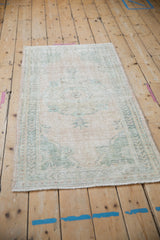 Worn texture and muted floral designs of a distressed vintage Oushak runner in cream and pale green.