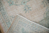 Distressed vintage Oushak close-up, showing worn pile, intact selvage, and hand knotted back.