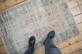 Textured vintage distressed Oushak rug displaying bright fuchsia blossoms and time-softened green tones.