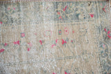 Distressed Oushak rug's worn pile, revealing fuchsia blossoms and muted ivory foundation.